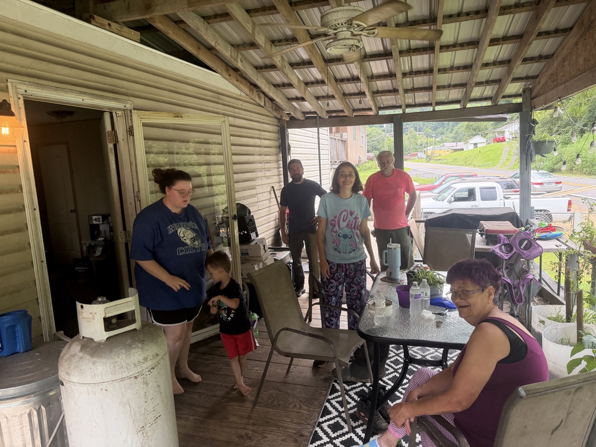 Neighbours in Raysal gathered with the team on their porch, sitting and talking together.