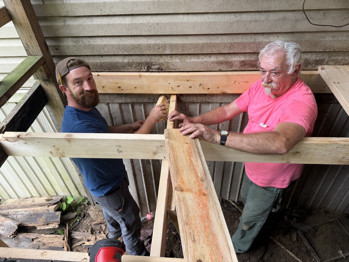 Two team members fitting new framing timbers for the porch.