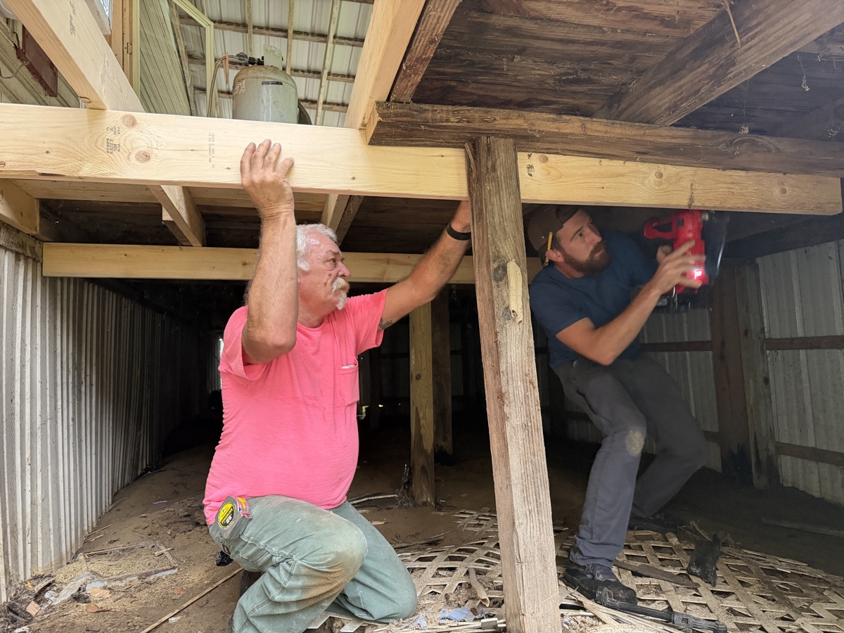 Team members working underneath the structure, setting joists in place.
